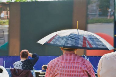 Şemsiyeli bir adam açık havada film izliyor..