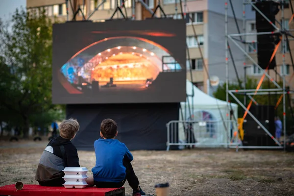 Open-air cinema. Children watching a movie on the screen of a summer cinema.