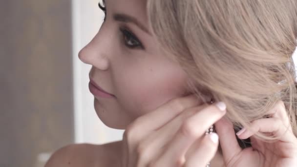 Η νεαρή και όμορφη γυναίκα βάζει τα σκουλαρίκια — Αρχείο Βίντεο