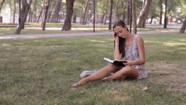 Mujer joven escribe en su diario en el parque — Vídeo de stock