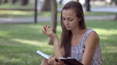 Genç kadın kitap ve yeme elma parkta okuma.