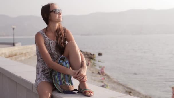 Mujer joven sentada y mirando al mar — Vídeos de Stock