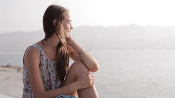 Jonge vrouw zit en kijkt op de zee — Stockvideo