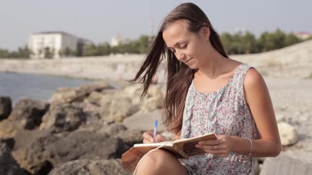 Yong Frau macht sich Notizen in Tagebuch am Strand — Stockvideo