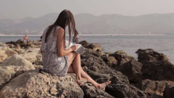 Yong vrouw maken van aantekeningen in dagboek op het strand — Stockvideo