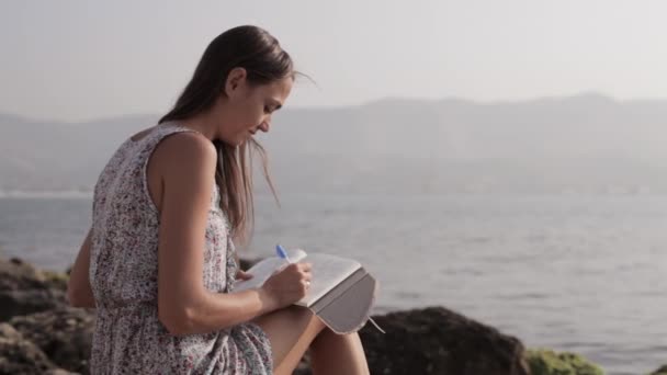 Wanita Yong membuat catatan di buku harian di pantai — Stok Video