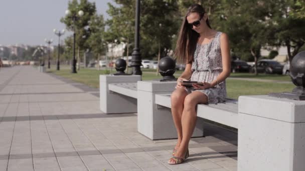 Ung kvinna med tablett i parken — Stockvideo