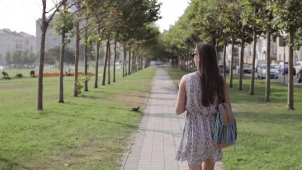 Jonge vrouw met een boek wandelen in het park. — Stockvideo