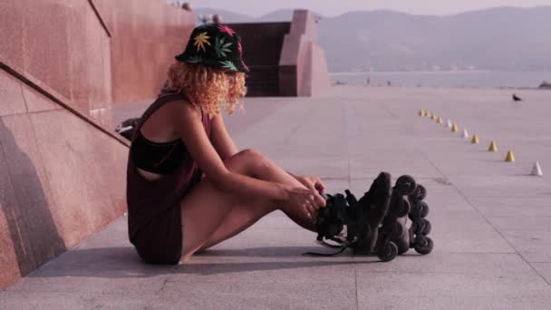 Menina adolescente bonito coloca patins em frente ao mar — Vídeo de Stock