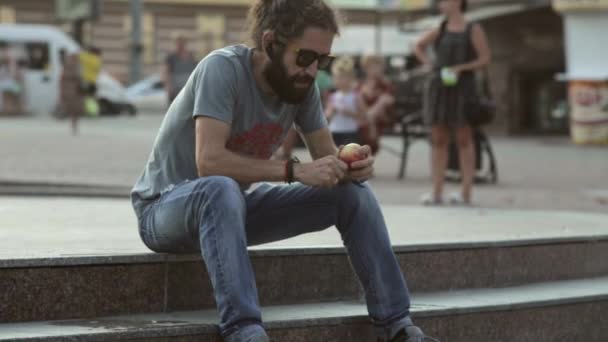 Mann schneidet und isst Apfel im Park — Stockvideo