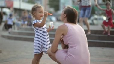 Anne ve kızı parkta kabarcıklar üfleme