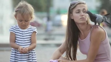 Anne ve küçük kız bir parkta güvercin besleme.