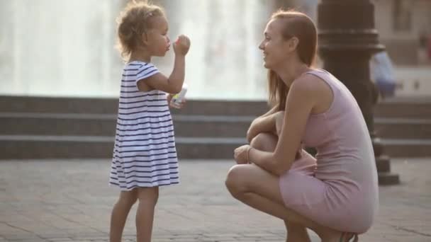 Madre e hija soplando burbujas en el parque — Vídeo de stock