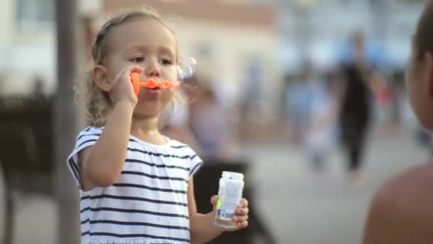 Sevimli küçük kız parkta sabun köpüğü üfleme. — Stok video