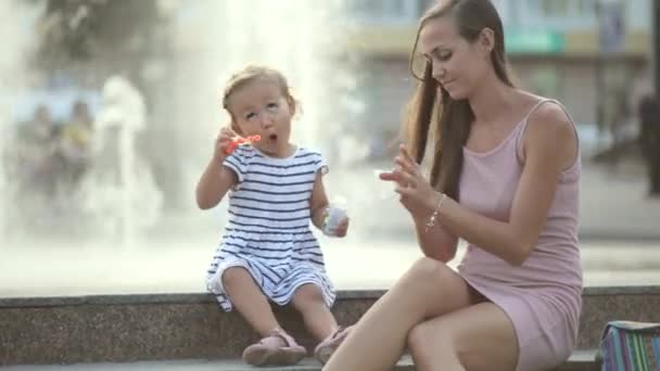 Madre e hija soplando burbujas en el parque — Vídeos de Stock