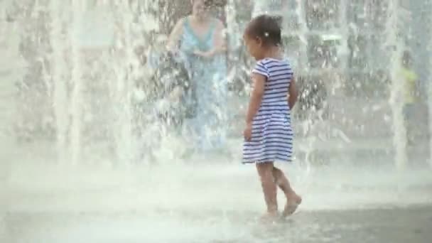 Linda niña corriendo a través de la fuente y ríe — Vídeos de Stock