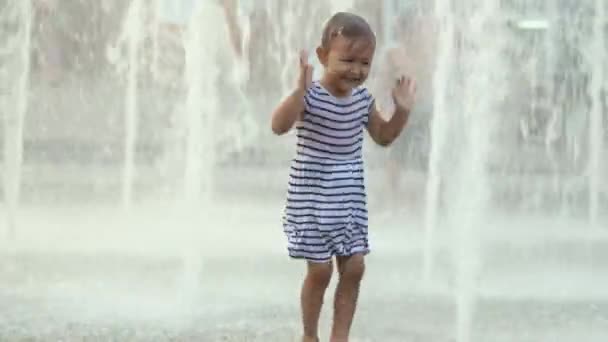 Carina bambina che corre attraverso la fontana, danza e ride — Video Stock