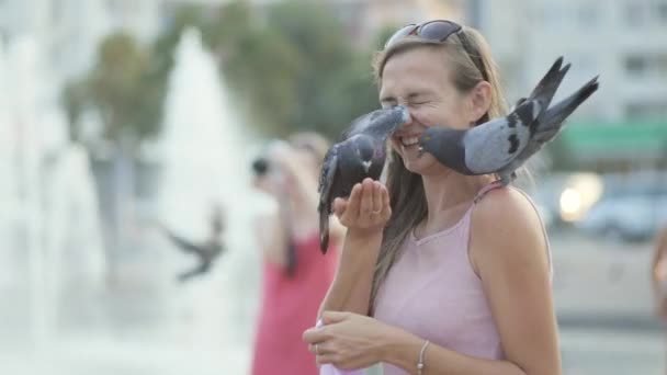 Attraente giovane donna che nutre piccioni nel parco — Video Stock