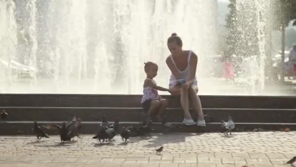 Madre y niña en un parque alimentando palomas . — Vídeo de stock