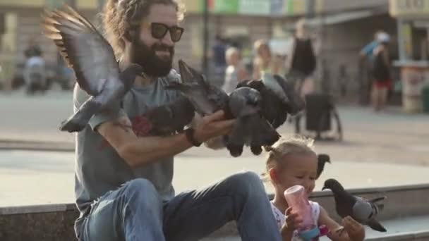 Hombre con hija alimentando palomas en el parque . — Vídeos de Stock