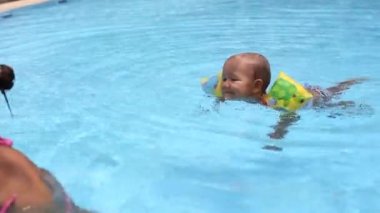 Anne küçük kız havuzda eğleniyor.