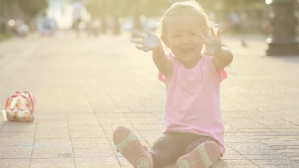 Schattig meisje bevuild met kalk, plezier en tonen haar vuile handen naar de camera — Stockvideo