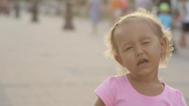 Милая маленькая девочка играет обезьяну, подмигивает и воздушный поцелуй в общественном парке — стоковое видео