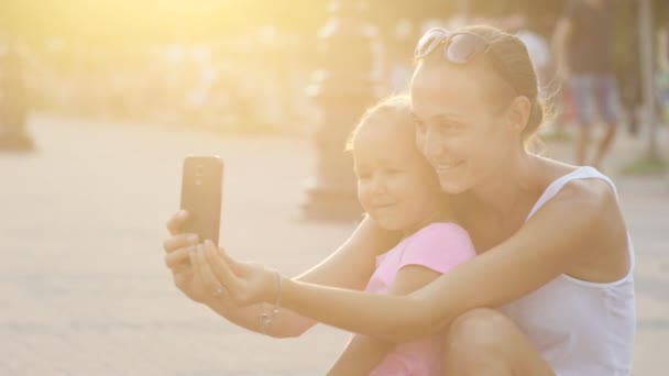 Çekici anne ve sevimli küçük kız eğleniyor ve selfie yapıyor — Stok video