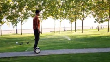 Bir adam deniz kenarında, yan manzaralı bir şekilde segway 'e doğru gidiyor.