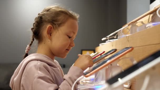 Malá holčička pomocí nového smartphonu na pultu v obchodě s elektronikou. — Stock video