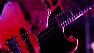 Gitarist konser sahnesinde elektro gitar çalıyor, yakın plan.