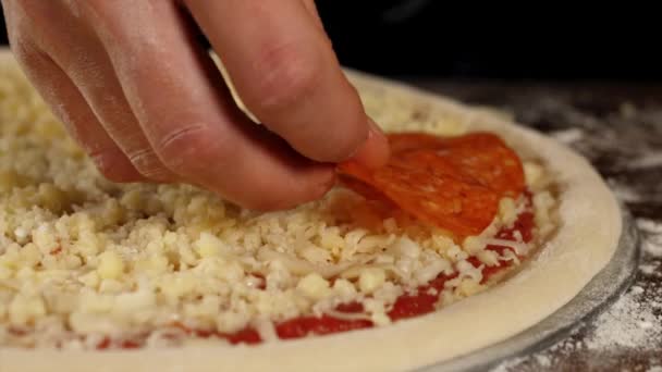 Ręka nakłada salami na pizzę, zbliżenie — Wideo stockowe