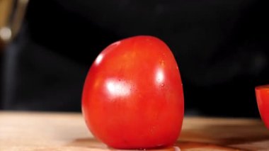 Eller ahşap tahtada bıçakla domates kesiyor.