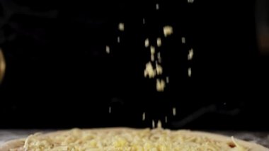 Peynir pizzanın üstüne düşüyor, yavaş çekimde yakın çekim..