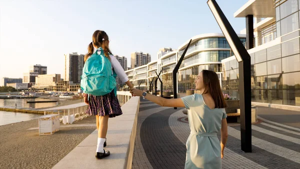 제복을 입은 어린 딸을 데리고 아침에 학교에 가는 어린 어머니 스톡 사진