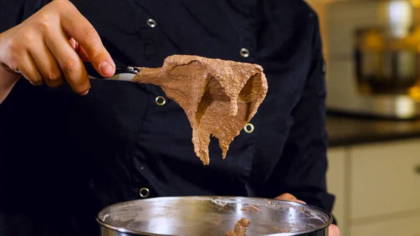 El cocinero está mezclando crema marrón en un tazón de acero para hacer el postre, primer plano —  Fotos de Stock