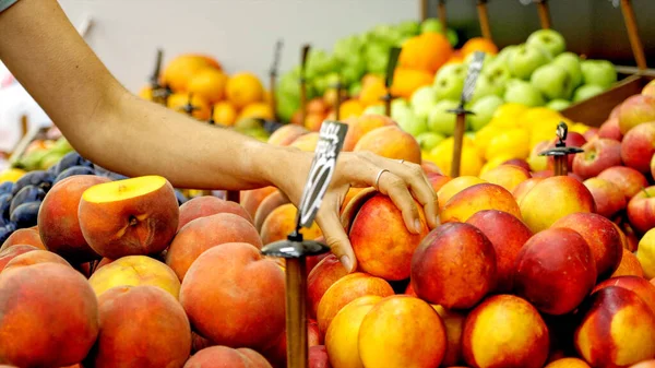 Joven mujer caucásica está eligiendo un nectarinas en el supermercado Fotos De Stock Sin Royalties Gratis