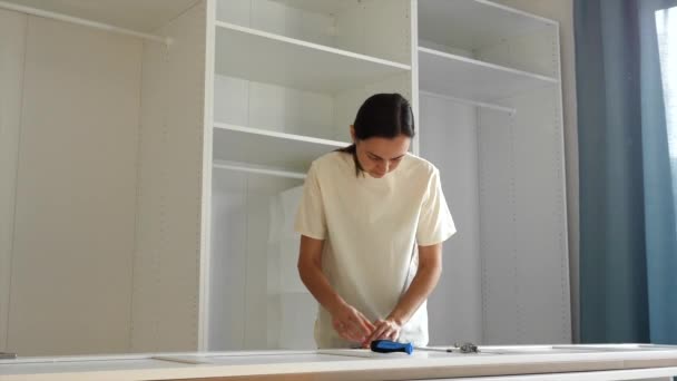 A young woman is installing the hinges on the doors of the closet — Stock Video