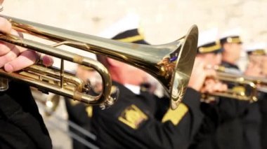 Bir rüzgar enstrümanı. Tanınmayan bir asker trompet çalıyor. Yakın plan.