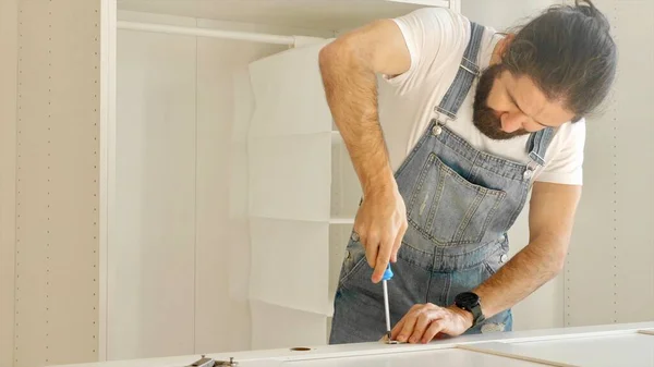 Un hombre está instalando las bisagras en las puertas del armario Fotos De Stock