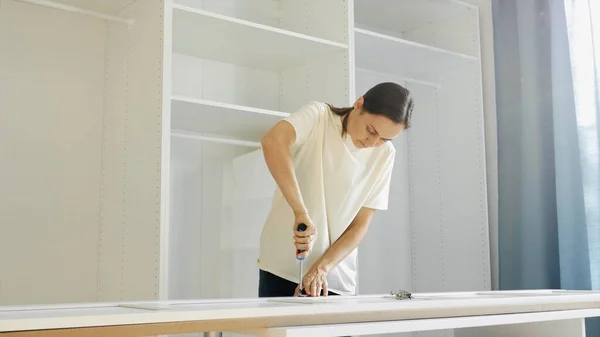 Una joven está instalando las bisagras en las puertas del armario Fotos De Stock