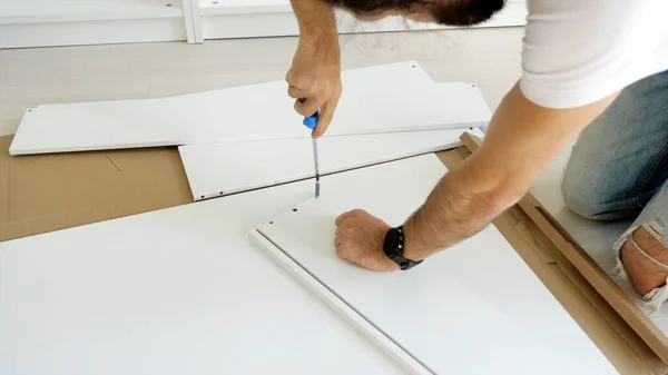 Un om asamblează sertarul pentru dulap. fotografii de stoc fără drepturi de autor