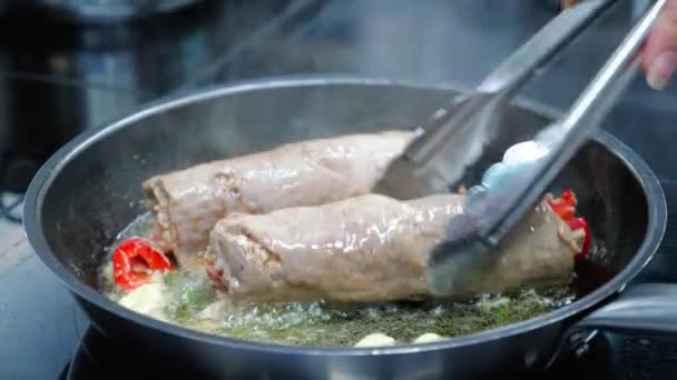 Lo chef sta cucinando due involtini di carne sott'olio su una padella, primo piano al rallentatore — Video Stock