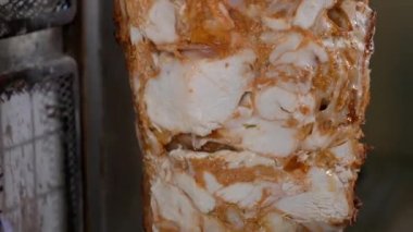 Bir aşçı shawarma yapmak için büyük bir bıçakla et kesiyor..