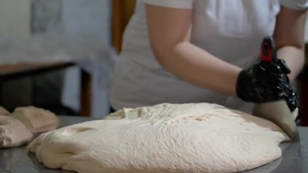 A woman is cutting a dough quickly by spatula — Wideo stockowe