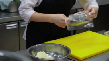 Tanınmayan şef, restoranın mutfağında film paketine elma koyar.