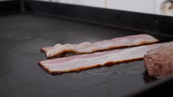 Köksmästare lägger bacon på grillen, närbild — Stockvideo