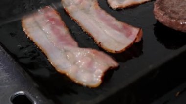 Şef pastırma ve köfte dilimlerini ızgarada ızgara hamburgere çeviriyor..