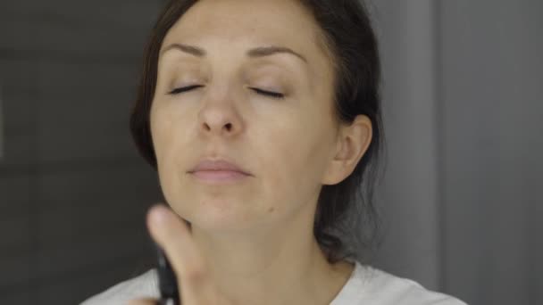 Tânăra femeie pulverizează apa micelară pe față — Videoclip de stoc
