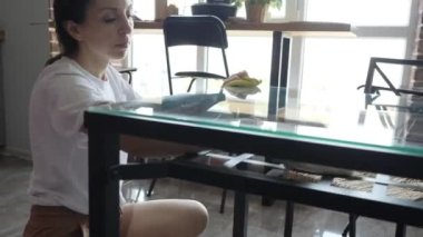 Kadın mutfaktaki mutfak masasını temizliyor.